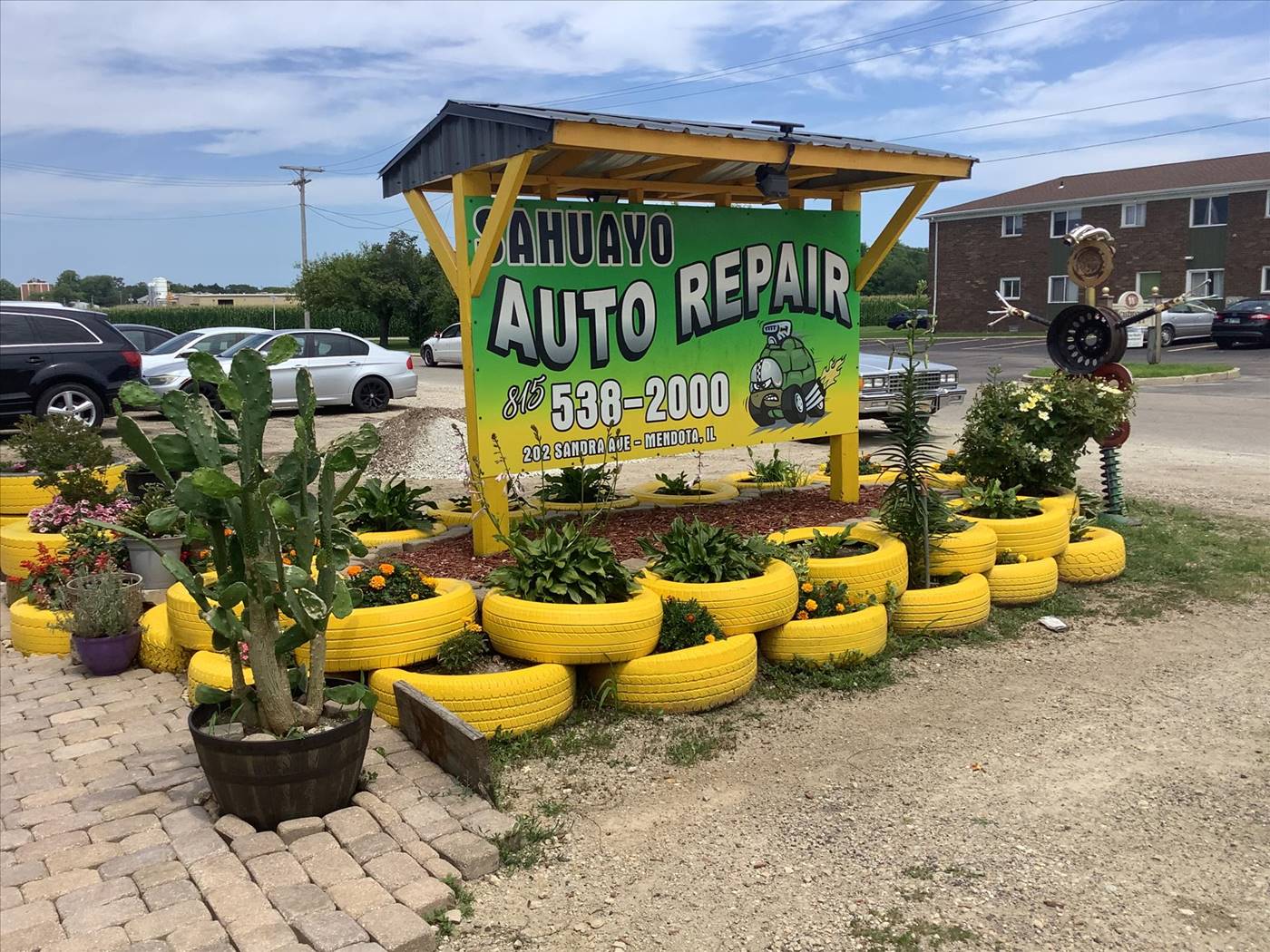 Sahuayo Auto Repair wood sign, yellow tire planters, and lot in Mendota